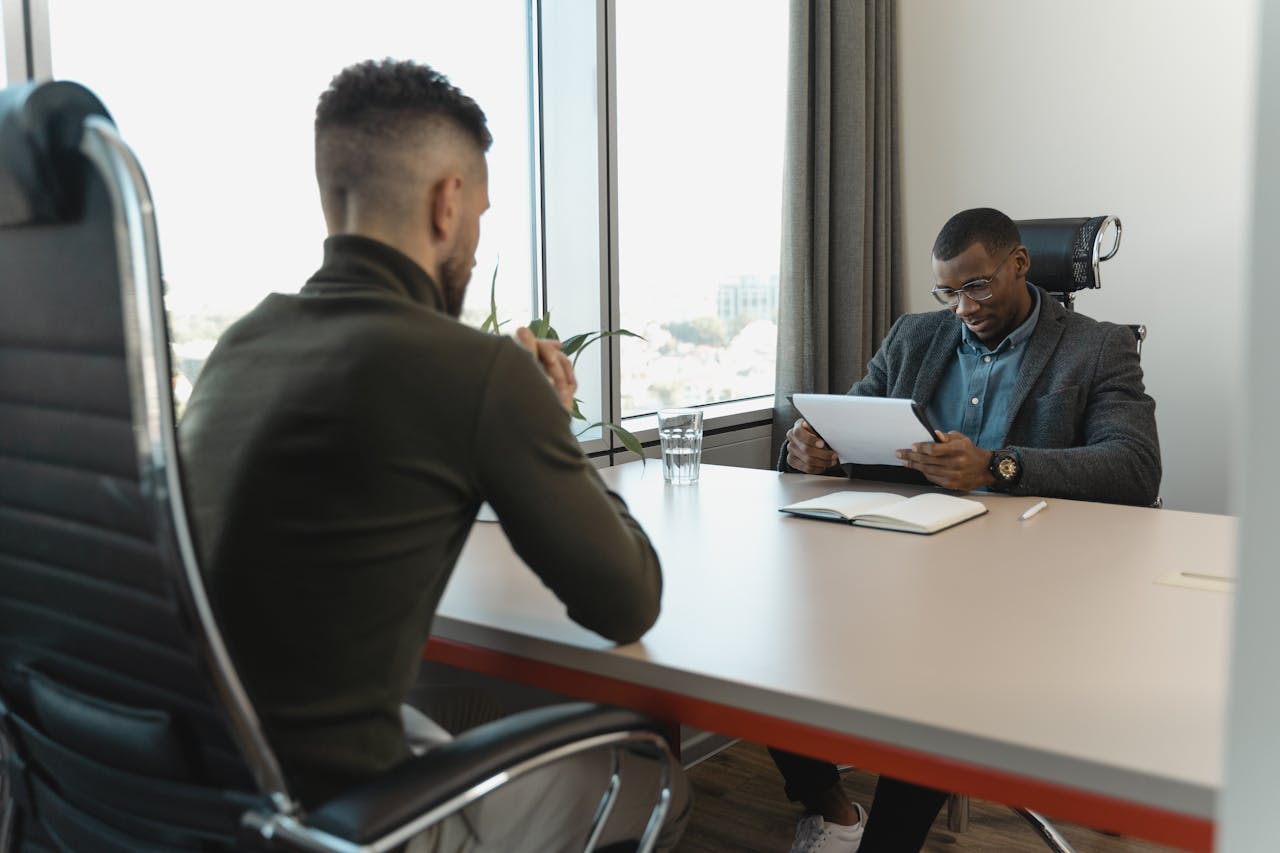 A job interview taking place in a modern office setting between two professional men.